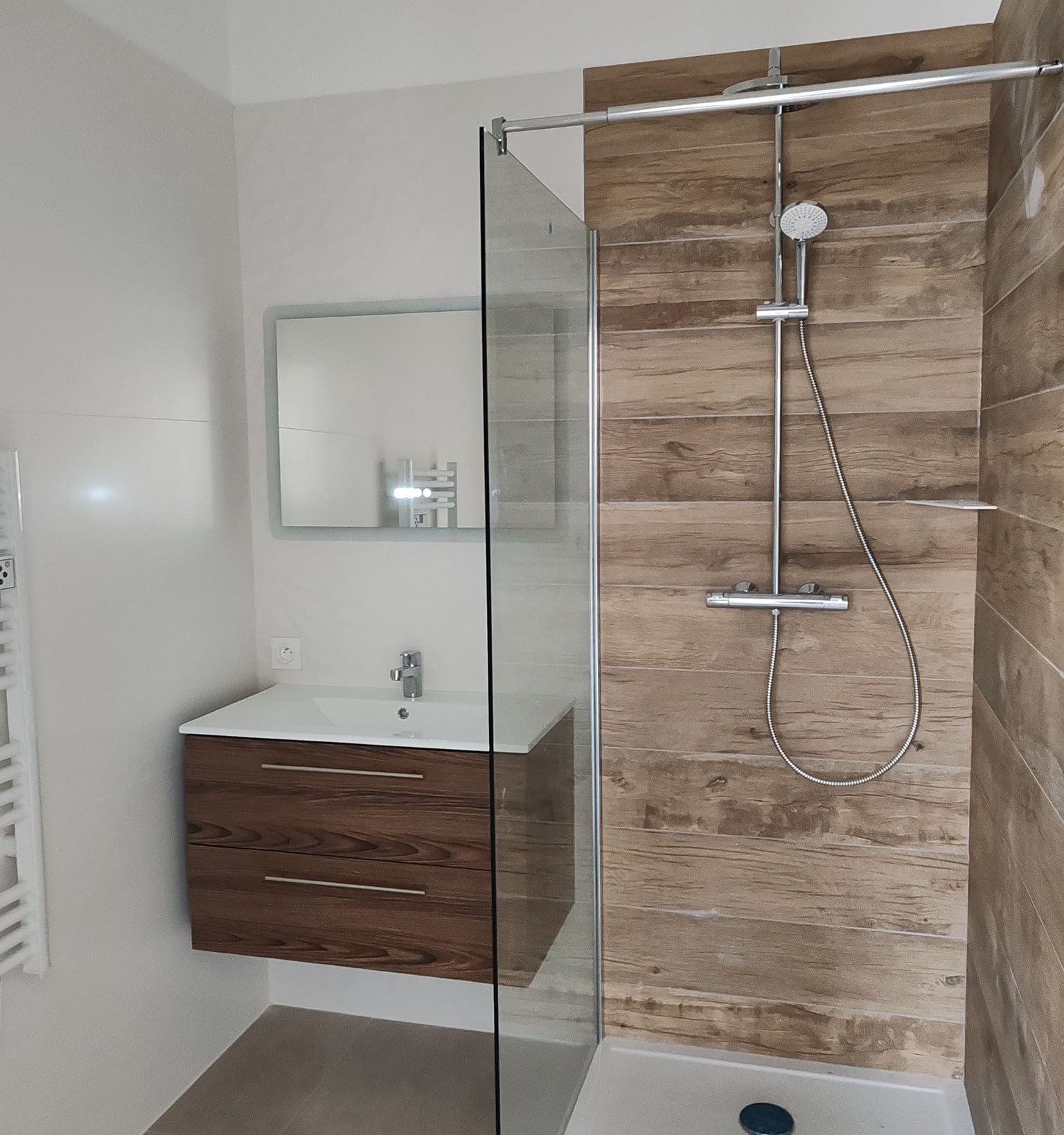 Salle de bain moderne : douche à l'italienne effet bois, meuble vasque suspendu et paroi de douche en verre.