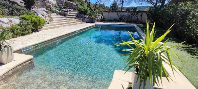 Piscine rectangulaire à l'eau turquoise avec terrasse en pierre et jardin paysager en paliers.